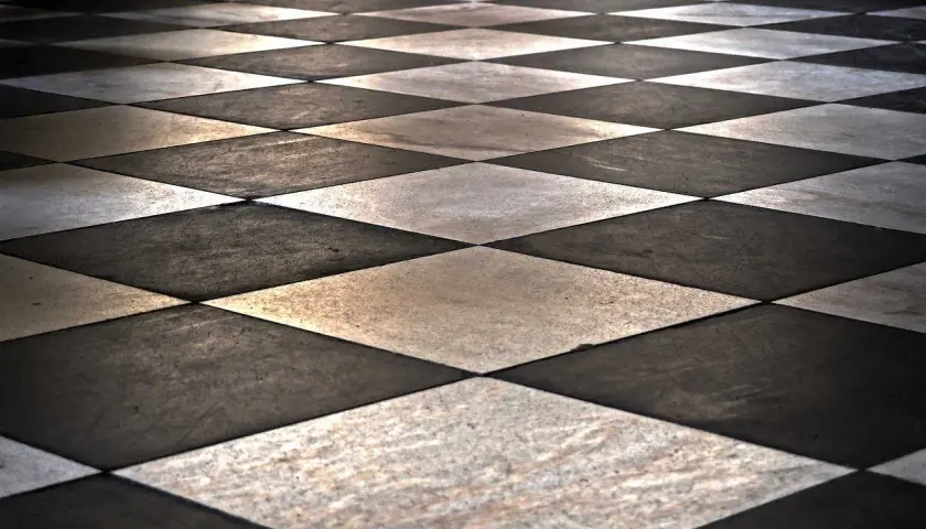 Pavimento a scacchi con posa piastrelle in diagonale, alternando marmo bianco e nero.