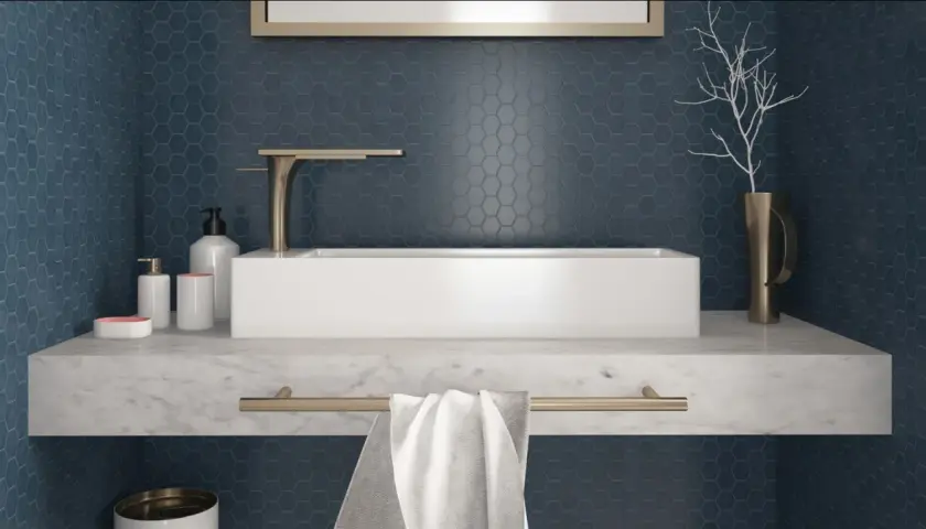 Un elegante bagno con un lavabo rettangolare bianco su un piano in marmo. Le pareti sono rivestite con un bellissimo posa mosaico esagonale blu scuro.