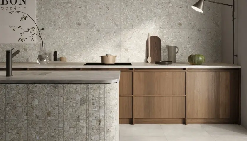 Cucina moderna con isola in **ceppo di gre** e rivestimenti a parete in grès effetto terrazzo.