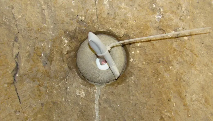 Dettaglio di un foro in muratura con un inserto in tessuto e un tubo, forse per il drenaggio o per i diatoni muratura.