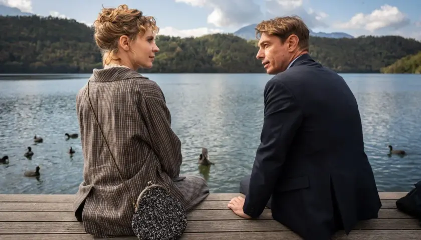 Coppia seduta su un pontile, con uno sguardo intenso. Nonostante i **wpc difetti** visibili, la scena evoca un'atmosfera di profonda connessione.