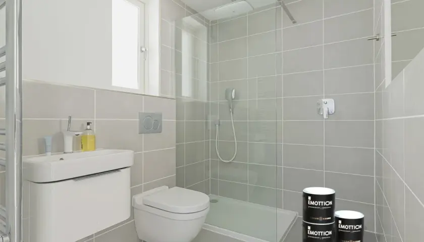 Bagno moderno con doccia, lavabo e WC. Due barattoli di pittura piastrelle bagno "Emottion" sono posizionati vicino alla doccia.