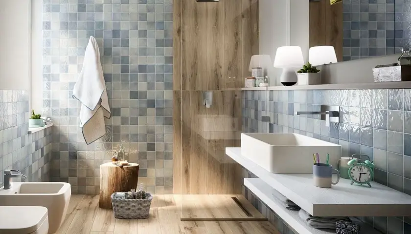 Bagno rustico contemporaneo con piastrelle azzurre e inserti in legno. Lavabo rettangolare, bidet e doccia a vista.