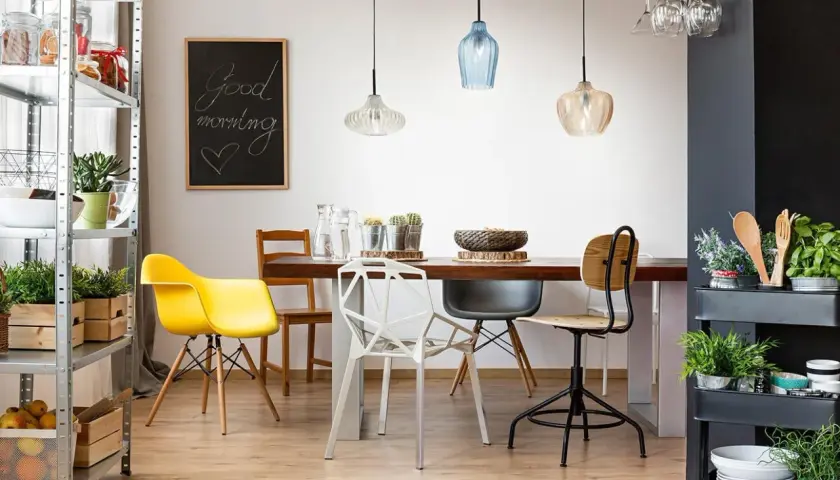 Tavolo da pranzo con sedie colorate e moderne, illuminato da lampade a sospensione. Ideale per chi vuole spostare punto luce soffitto e creare un ambiente accogliente.
