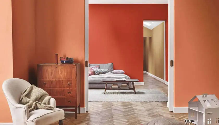 Un soggiorno accogliente con pareti arancioni, un divano letto e un mobile vintage. Perfetto per chi vuole imbiancare casa con stile.