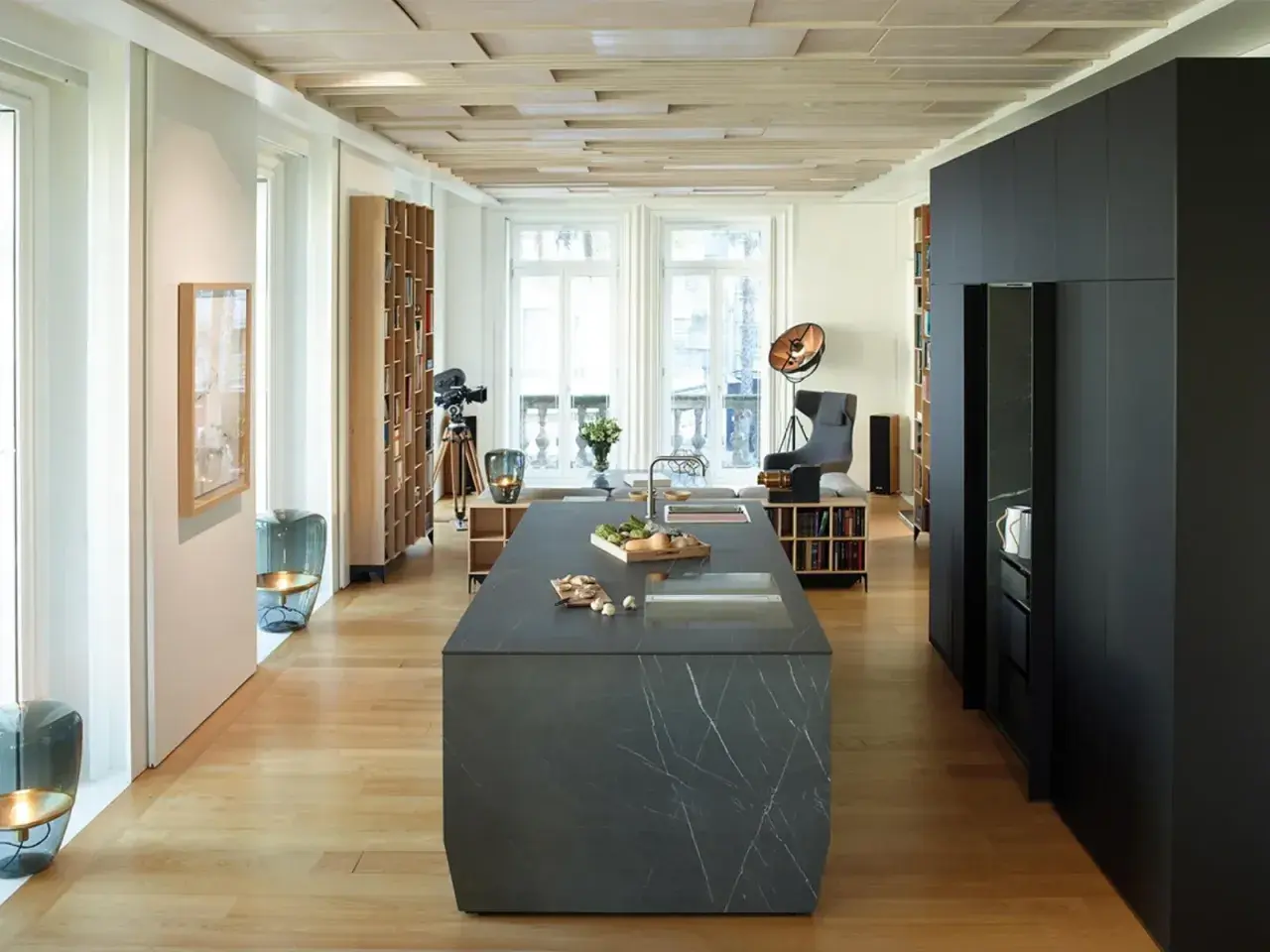 Cucina moderna con isola in pietra, parquet chiaro e dettagli in cementine.