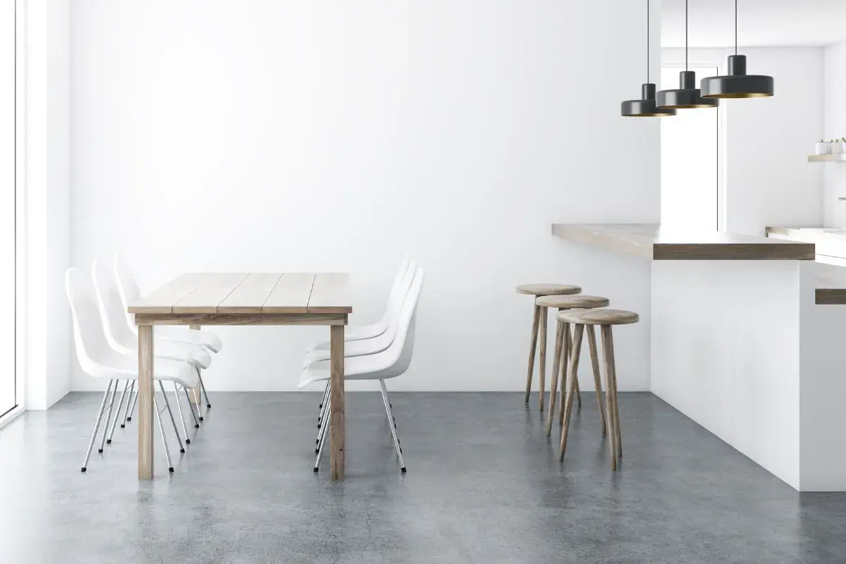 Tavolo in legno con sedie bianche e sgabelli al bancone, su un elegante **pavimento senza fughe**.