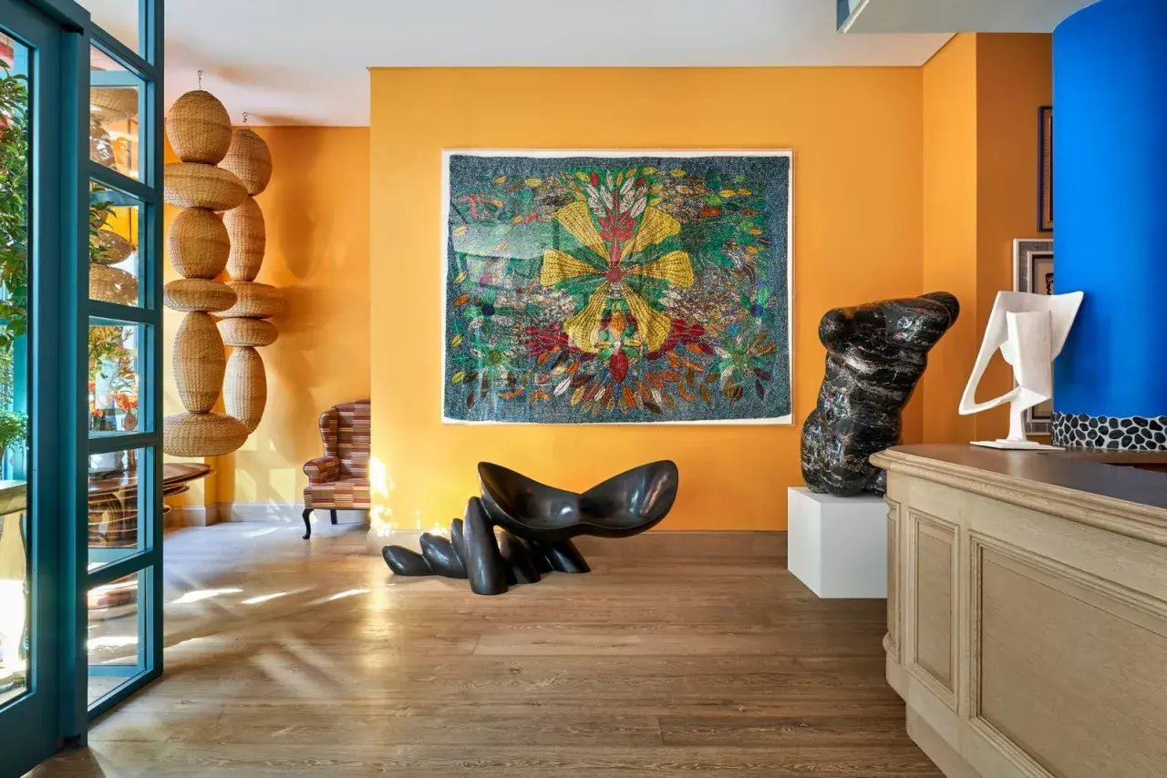 Un soggiorno vibrante con pareti arancioni che esaltano gli effetti pittura pareti moderne. Sculture audaci e un arazzo colorato creano un'atmosfera artistica.