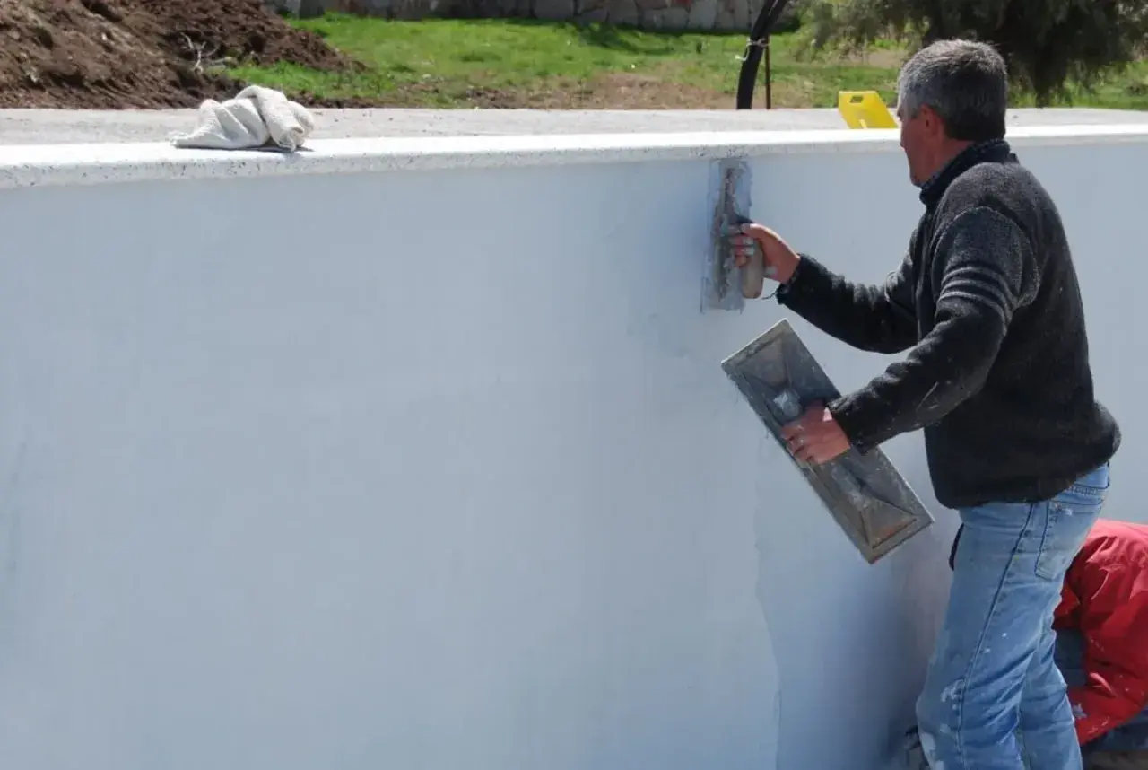 Operaio stende malta bastarda su un muro. Questo materiale serve per intonaci e murature, garantendo resistenza e durabilità.