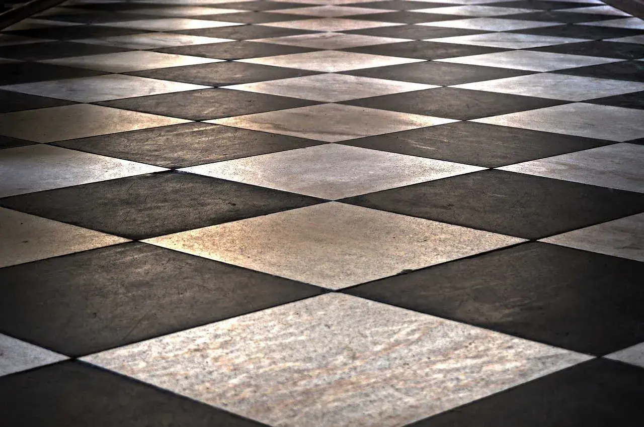 Pavimento a scacchi con posa piastrelle in diagonale, alternando marmo bianco e nero.