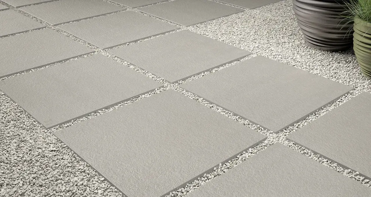 Posa a secco su ghiaia: lastre quadrate grigie alternate a ghiaia bianca, creando un percorso moderno e pulito.