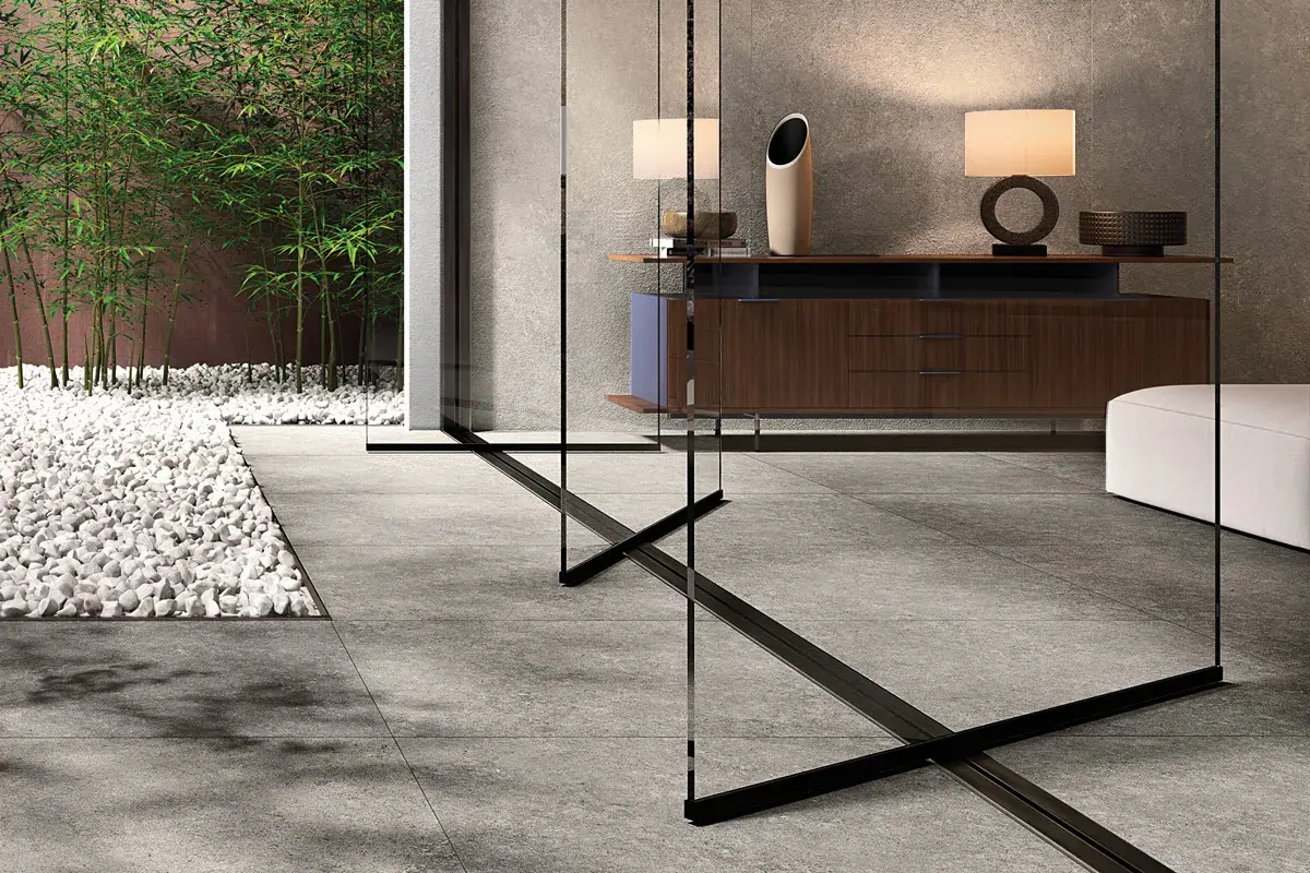 Un elegante soggiorno con arredi moderni e un giardino zen con bambù, evocando la raffinatezza del cotto d'Este.