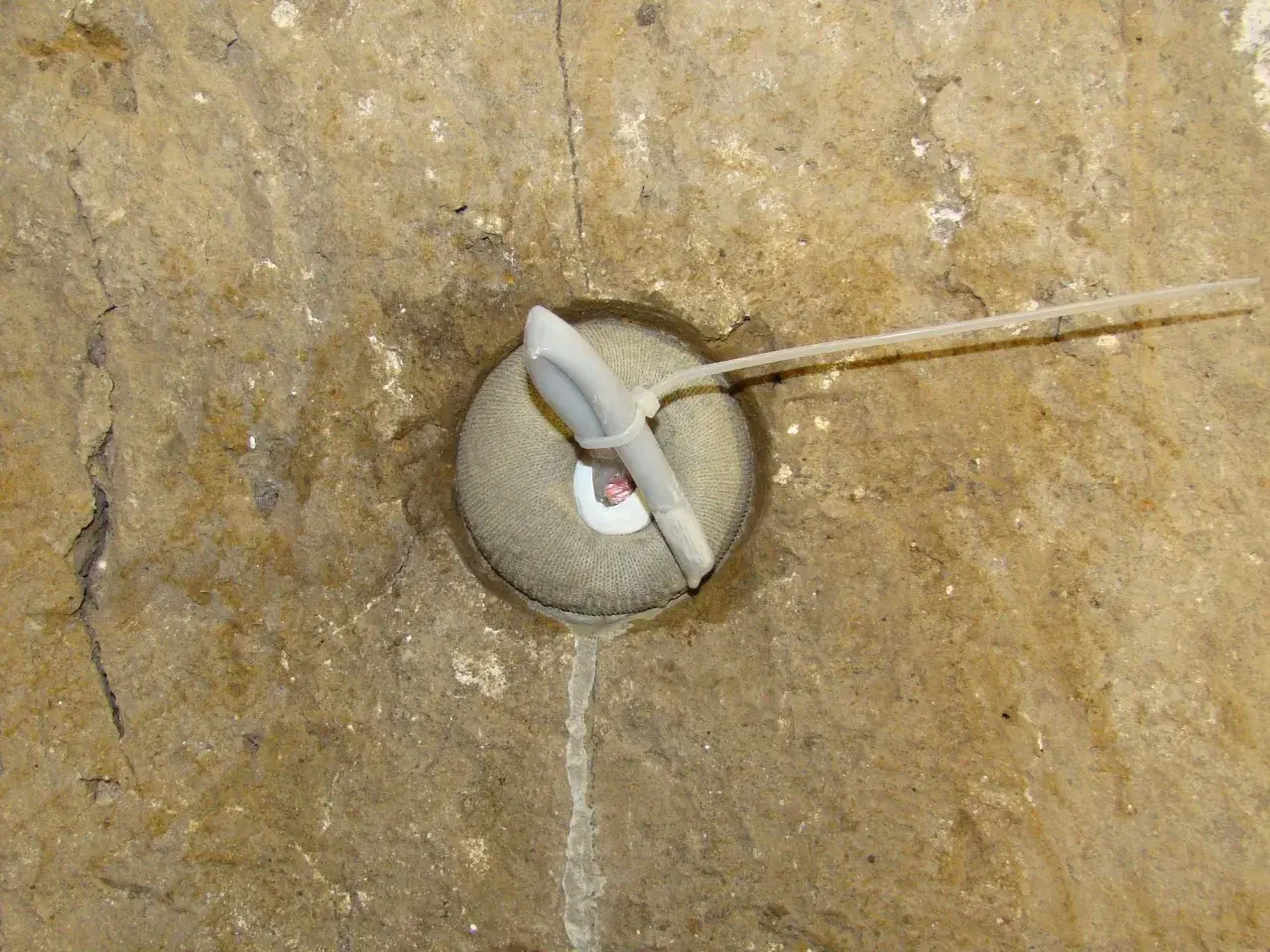 Dettaglio di un foro in muratura con un inserto in tessuto e un tubo, forse per il drenaggio o per i diatoni muratura.