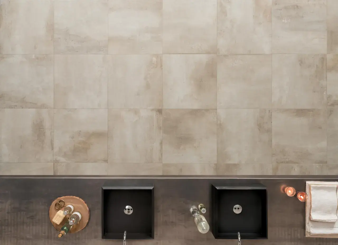 Bagno moderno con due lavabi neri, accessori e un rivestimento in gres tutta massa effetto pietra.