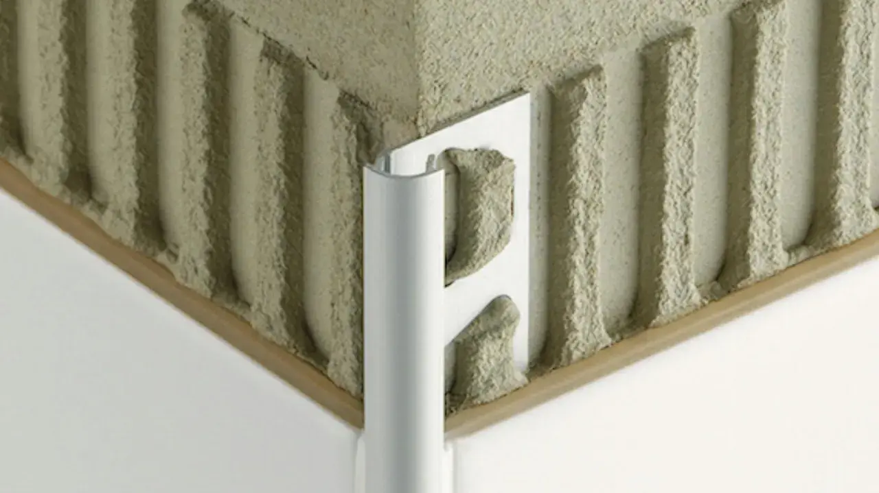 Angolo di un muro con adesivo per piastrelle e un elegante bordino piastrelle in alluminio.