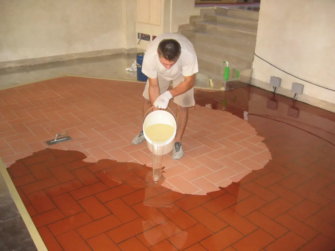 Uomo versa resina per coprire piastrelle cucina, creando una superficie lucida e moderna.