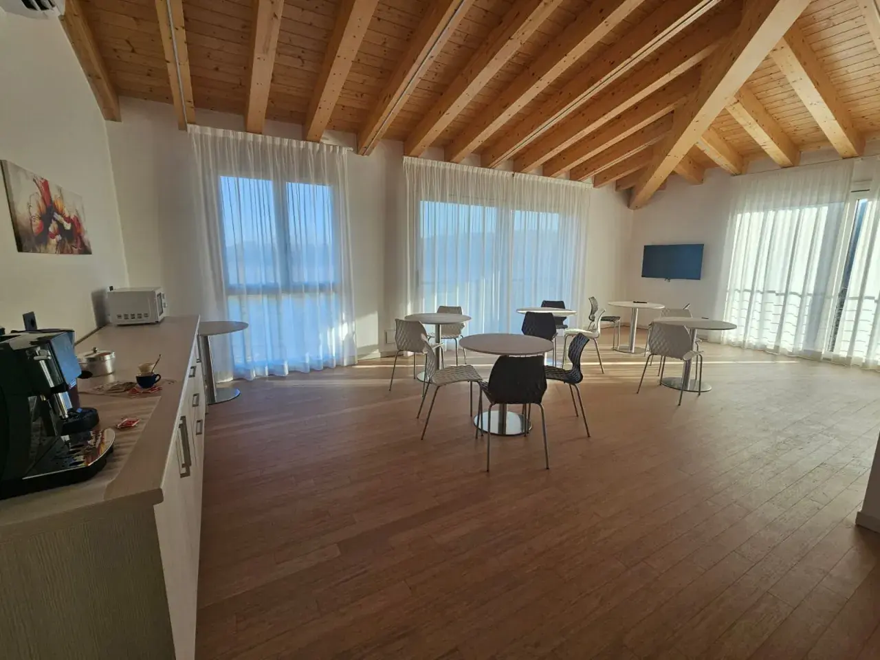 Pavimento per mansarda in legno chiaro, con travi a vista e arredi moderni.