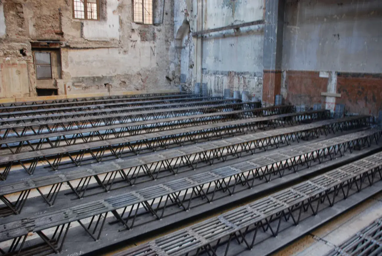 Strutture metalliche a traliccio pronte per essere posizionate per come rinforzare un solaio da sotto. L'ambiente è in fase di ristrutturazione.