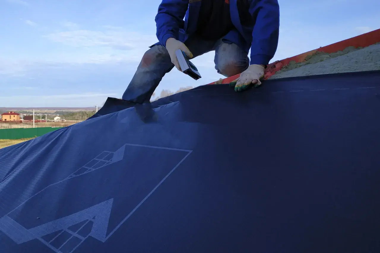 Installazione di una barriera al vapore su un tetto. La scheda tecnica del materiale è visibile.