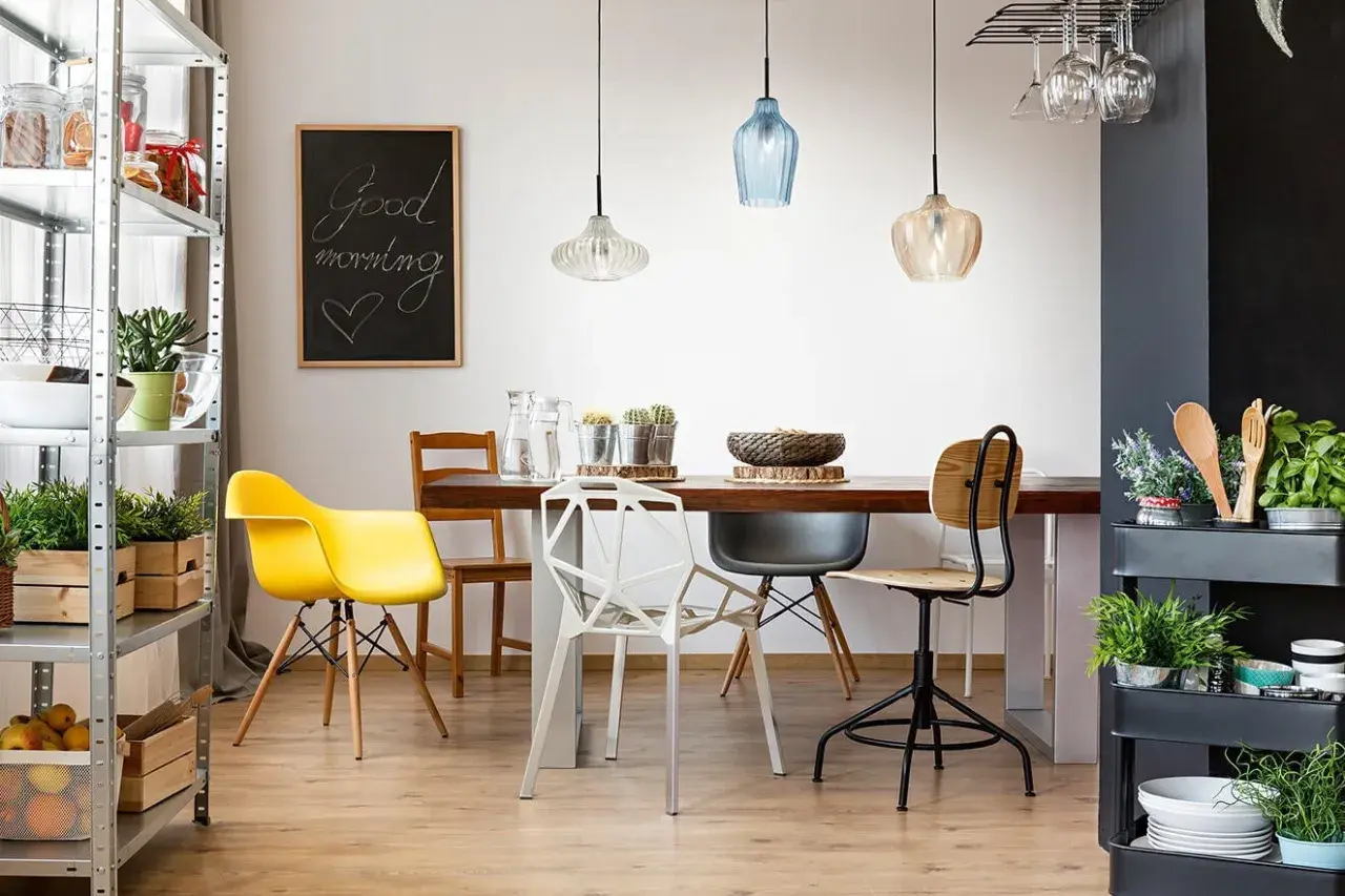 Tavolo da pranzo con sedie colorate e moderne, illuminato da lampade a sospensione. Ideale per chi vuole spostare punto luce soffitto e creare un ambiente accogliente.