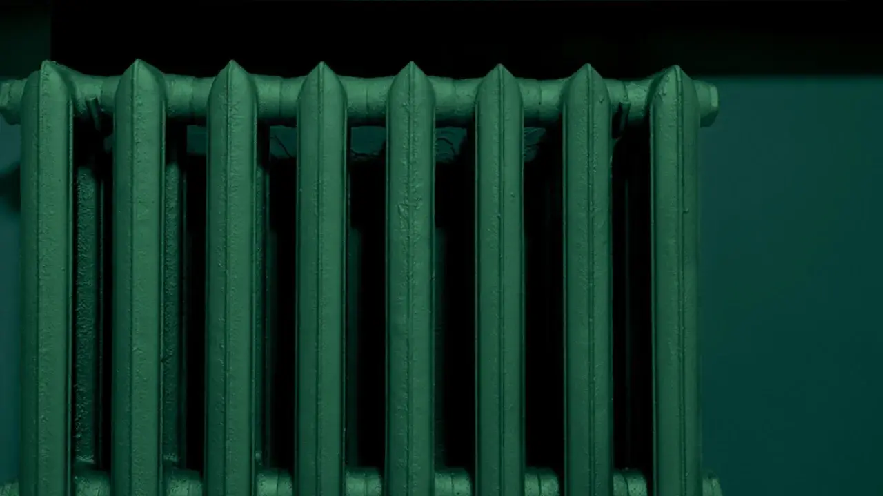 Un termosifone in ghisa, appena verniciato di un verde scuro e profondo, pronto a scaldare l'ambiente.