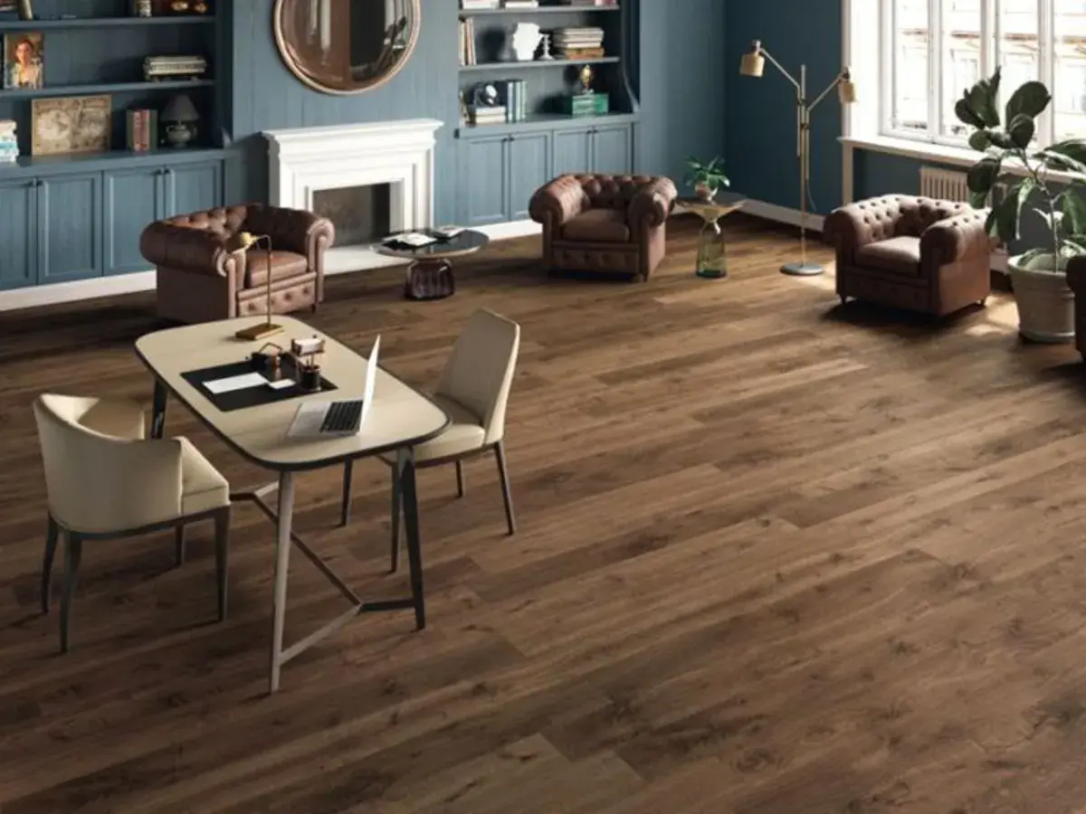 Un elegante soggiorno con camino, poltrone in pelle e un tavolo da lavoro. Il pavimento in legno scuro, perfetto per la posa pavimenti, completa l'arredamento.