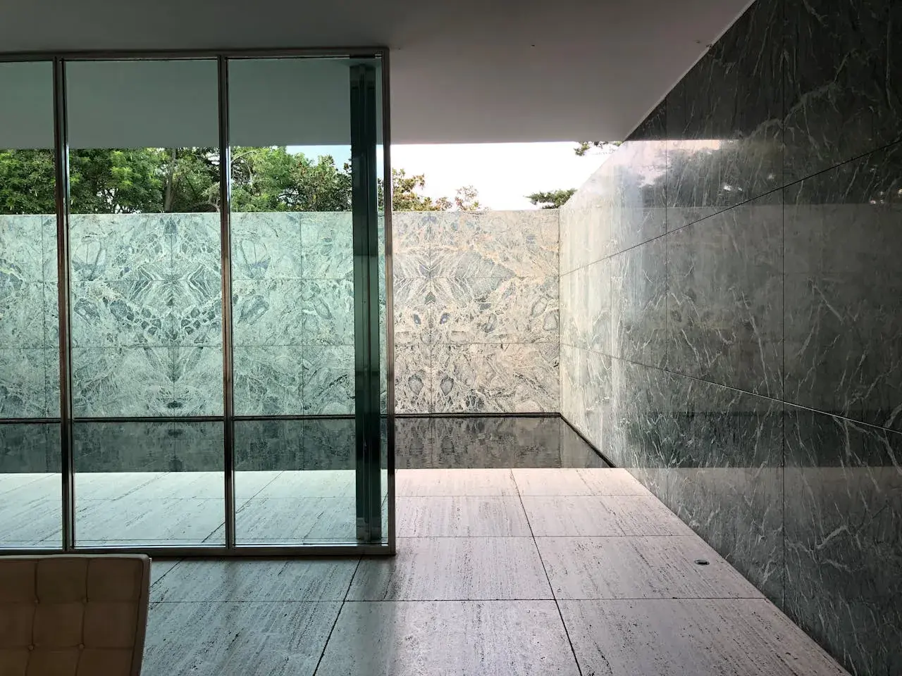 Pavimenti in travertino pro e contro: un'elegante terrazza con pareti in marmo verde e un piccolo specchio d'acqua.