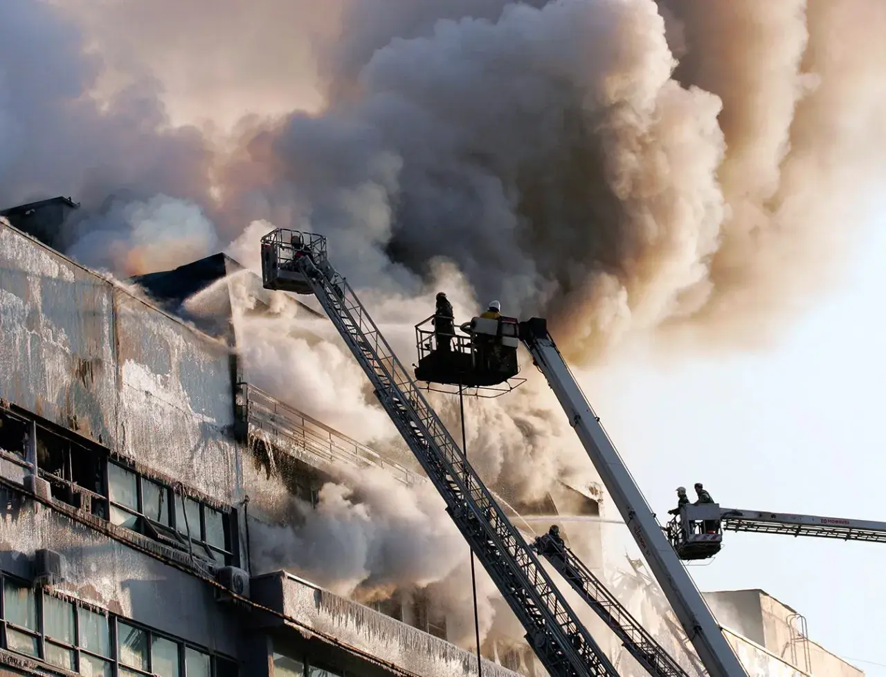 Vigili del fuoco da piattaforme aeree combattono un incendio in un edificio, dimostrando che la lana di roccia è ignifuga.