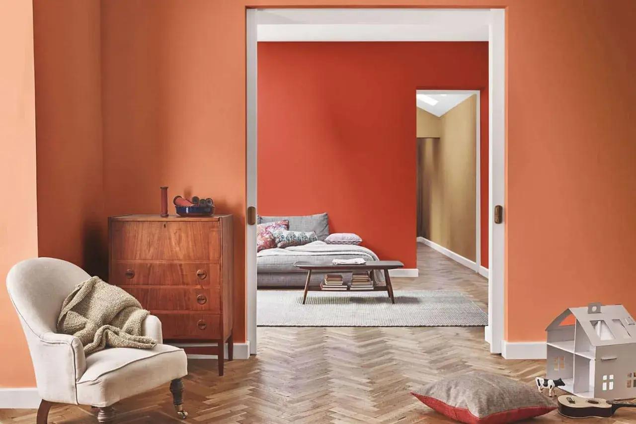 Un soggiorno accogliente con pareti arancioni, un divano letto e un mobile vintage. Perfetto per chi vuole imbiancare casa con stile.