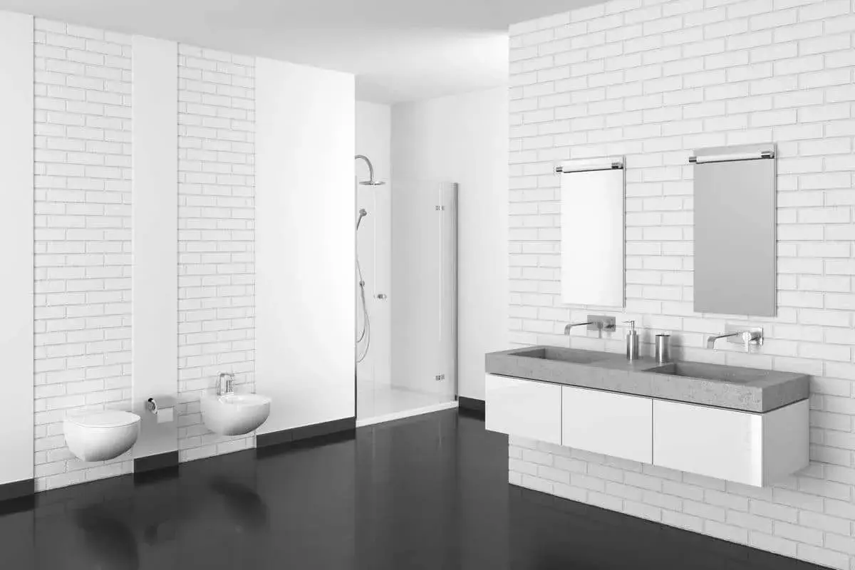 Bagno moderno con pavimenti in resina scura, sanitari sospesi, doccia a scomparsa e doppio lavabo in cemento.