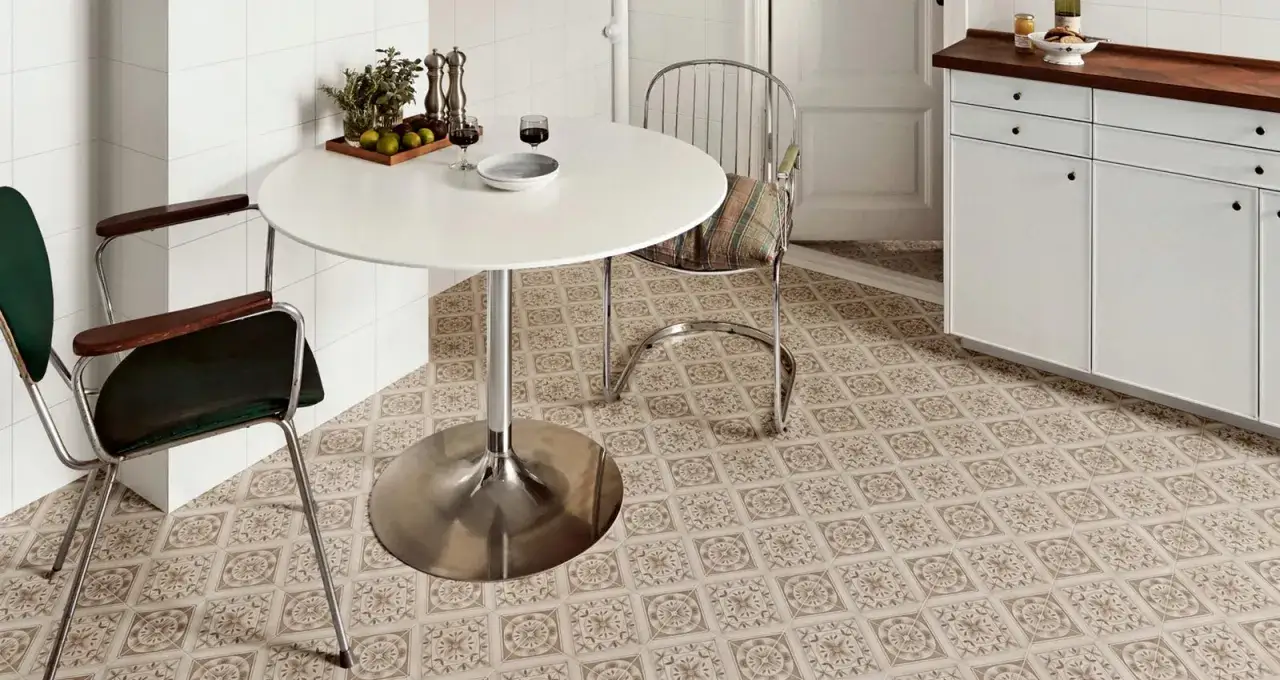 Un angolo cucina con tavolo rotondo e sedie vintage, su un pavimento decorato con motivi che ricordano le cementine, un classico intramontabile.