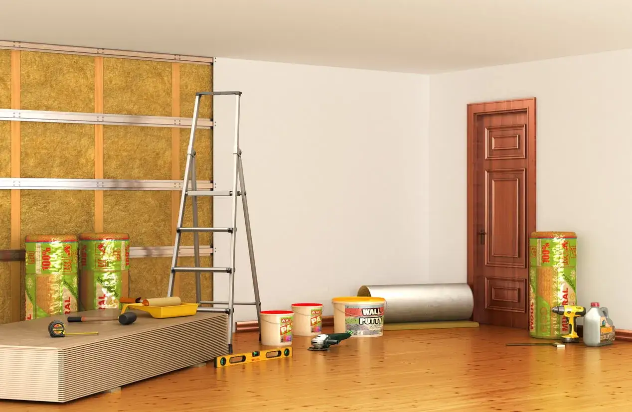 Materiali per isolamento termico e acustico, tra cui rotoli di lana minerale per un efficace cappotto interno antimuffa. Attrezzi da lavoro e pannelli in cartongesso pronti per l'installazione.