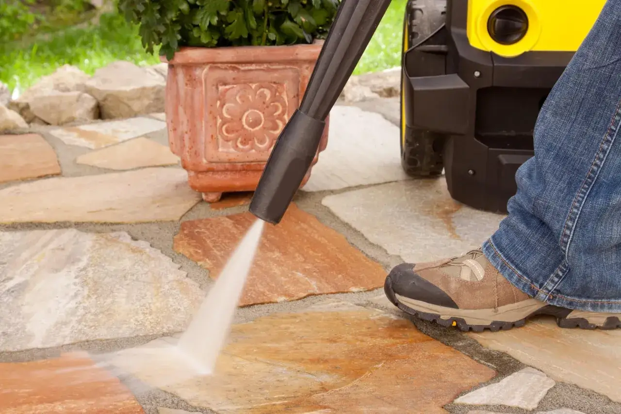 Pulire cotto esterno con idropulitrice per un patio splendente. Un getto d'acqua potente rimuove lo sporco dalle lastre di pietra.