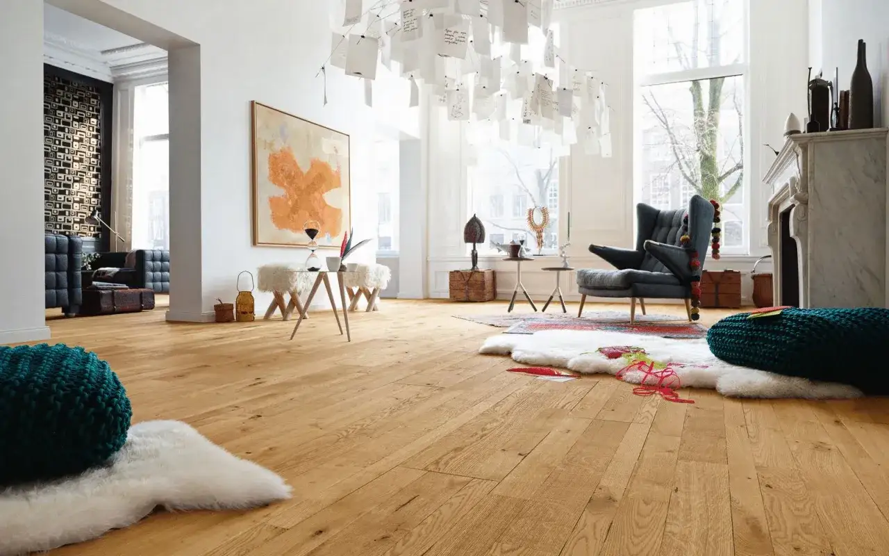 Un soggiorno luminoso con un miglior parquet in legno chiaro, arredi moderni e un'installazione artistica al soffitto.