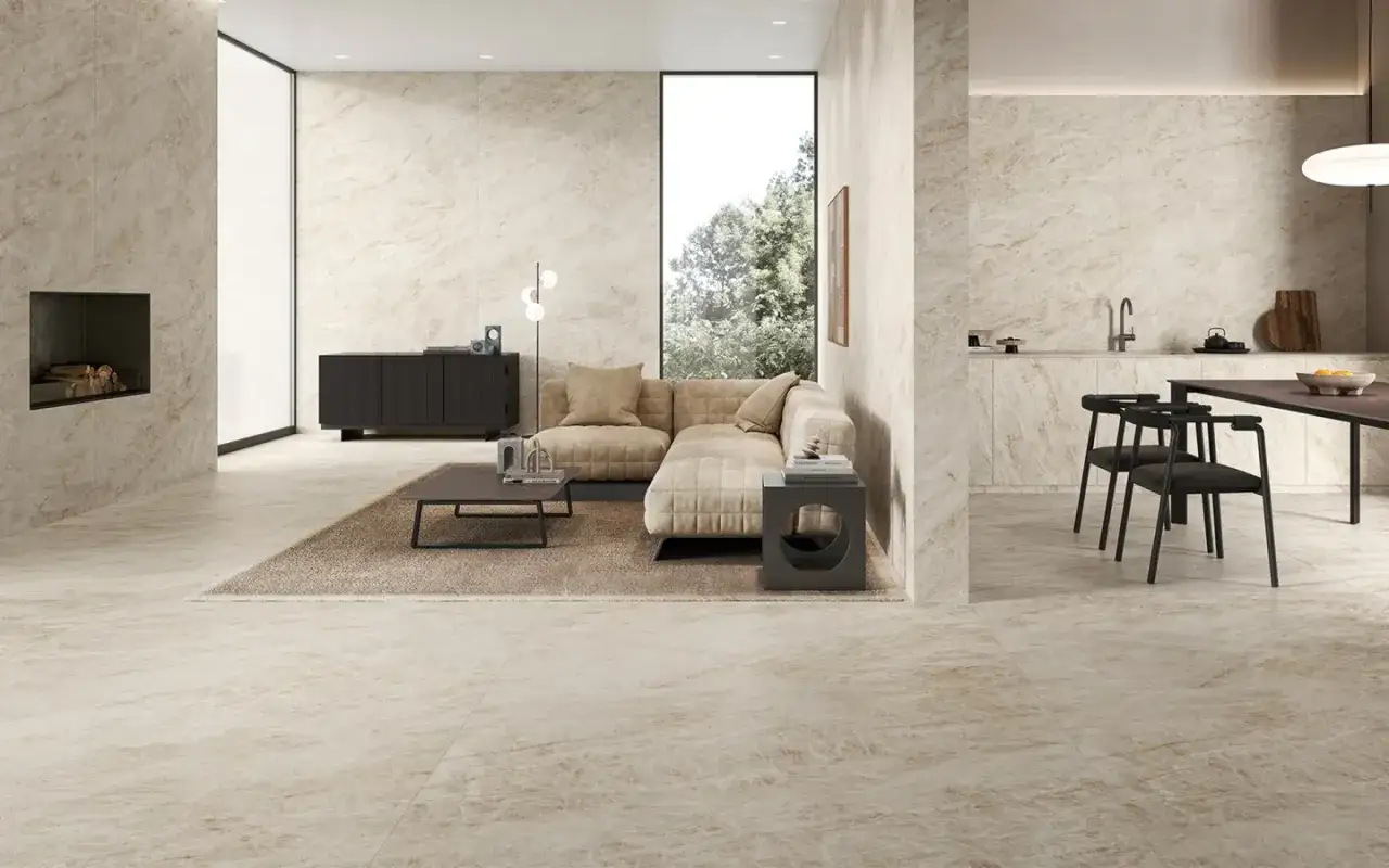 Soggiorno moderno con camino, divano beige e cucina a vista. Le fughe del pavimento in gres porcellanato color crema si integrano perfettamente con le pareti.