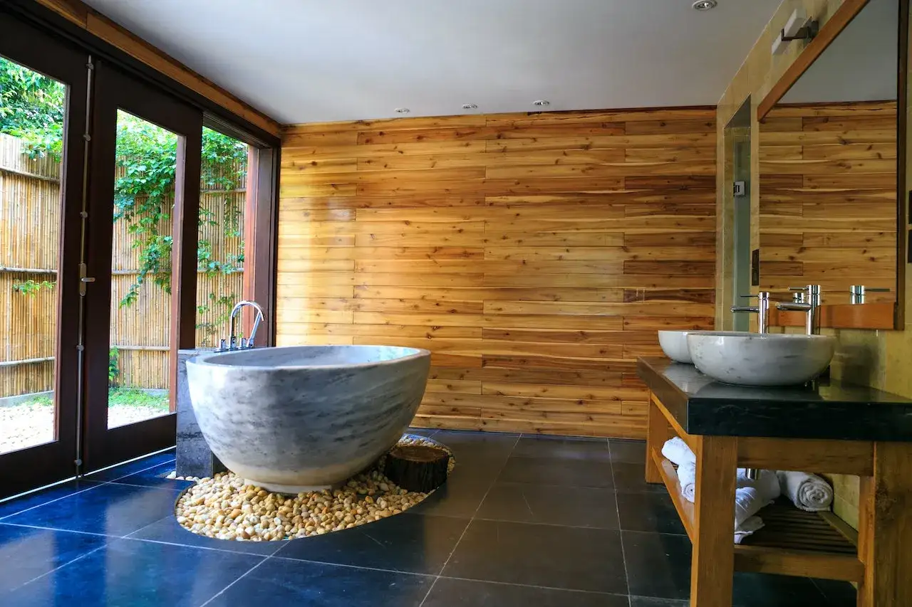 Bagno rustico contemporaneo con vasca in pietra, lavabi in marmo e pareti in legno.