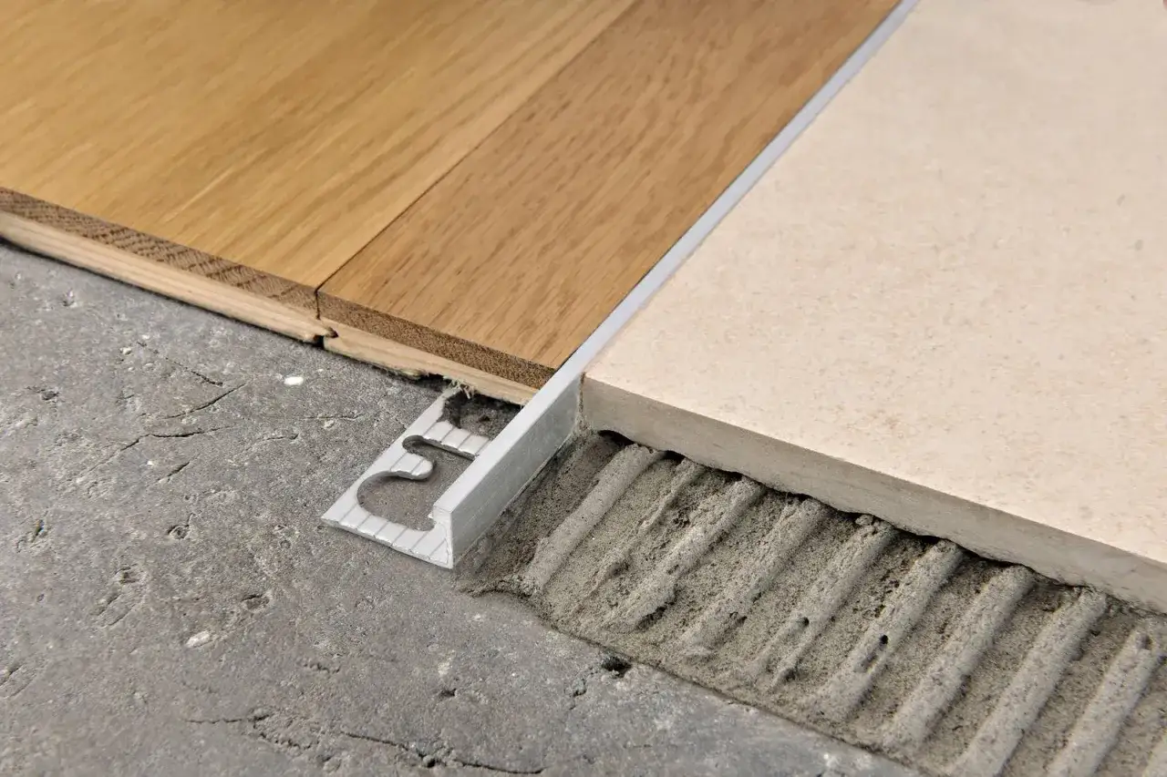 Profili metallici per accostare pavimenti diversi, come parquet e piastrelle, garantendo una finitura pulita e sicura.