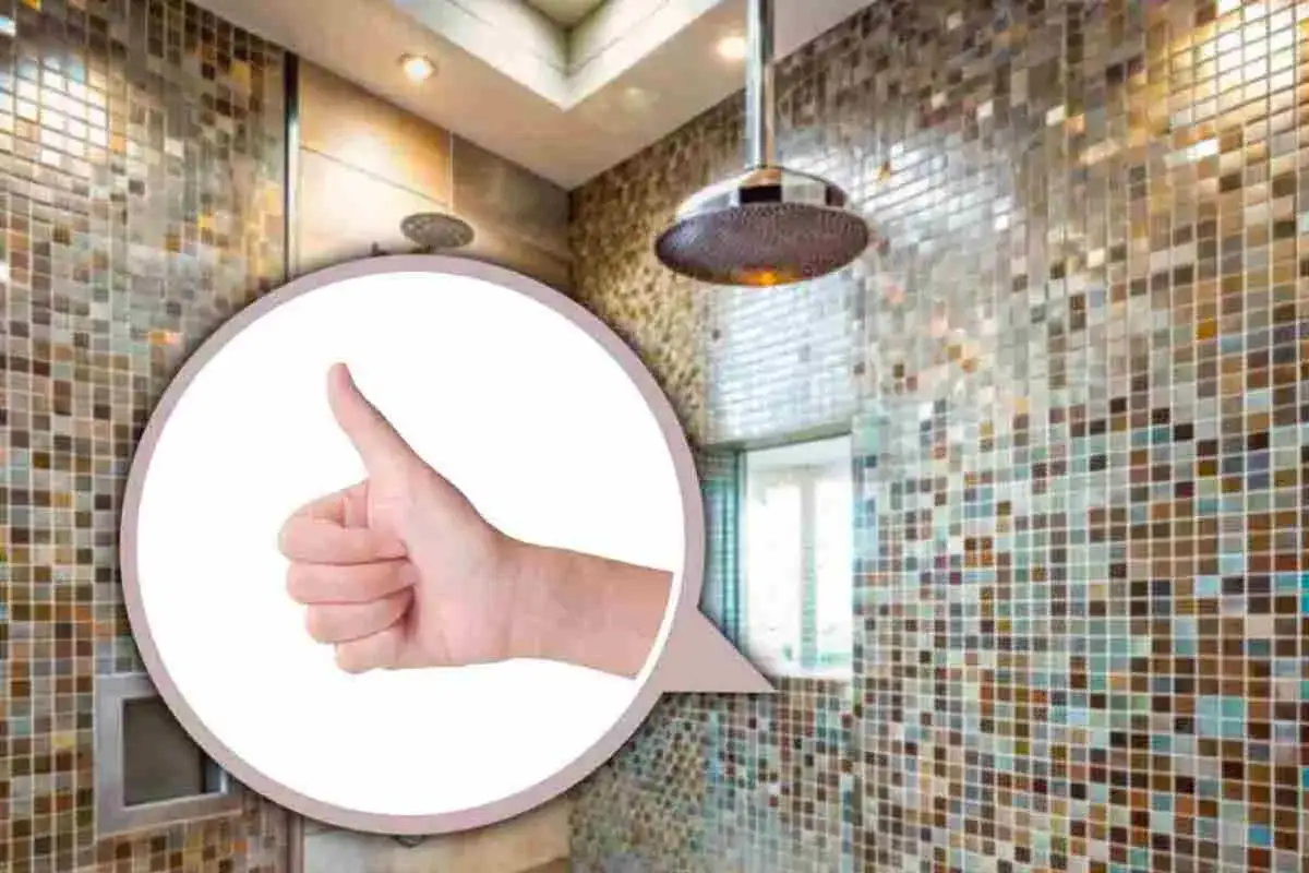 Mano con pollice in su su sfondo di mosaico doccia colorato. Scopri come pulire mosaico doccia per un risultato impeccabile.
