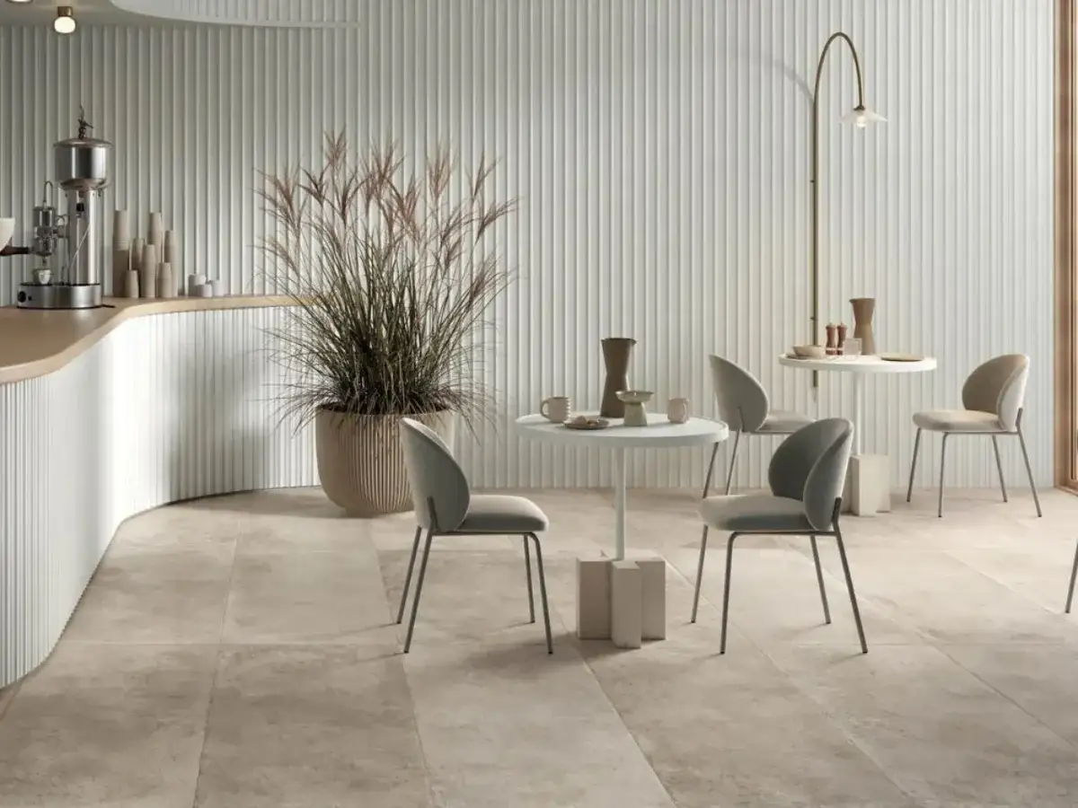Pavimento in piastrelle seconda scelta, con lievi difetti che aggiungono carattere. Ambiente moderno con piante e tavolini.