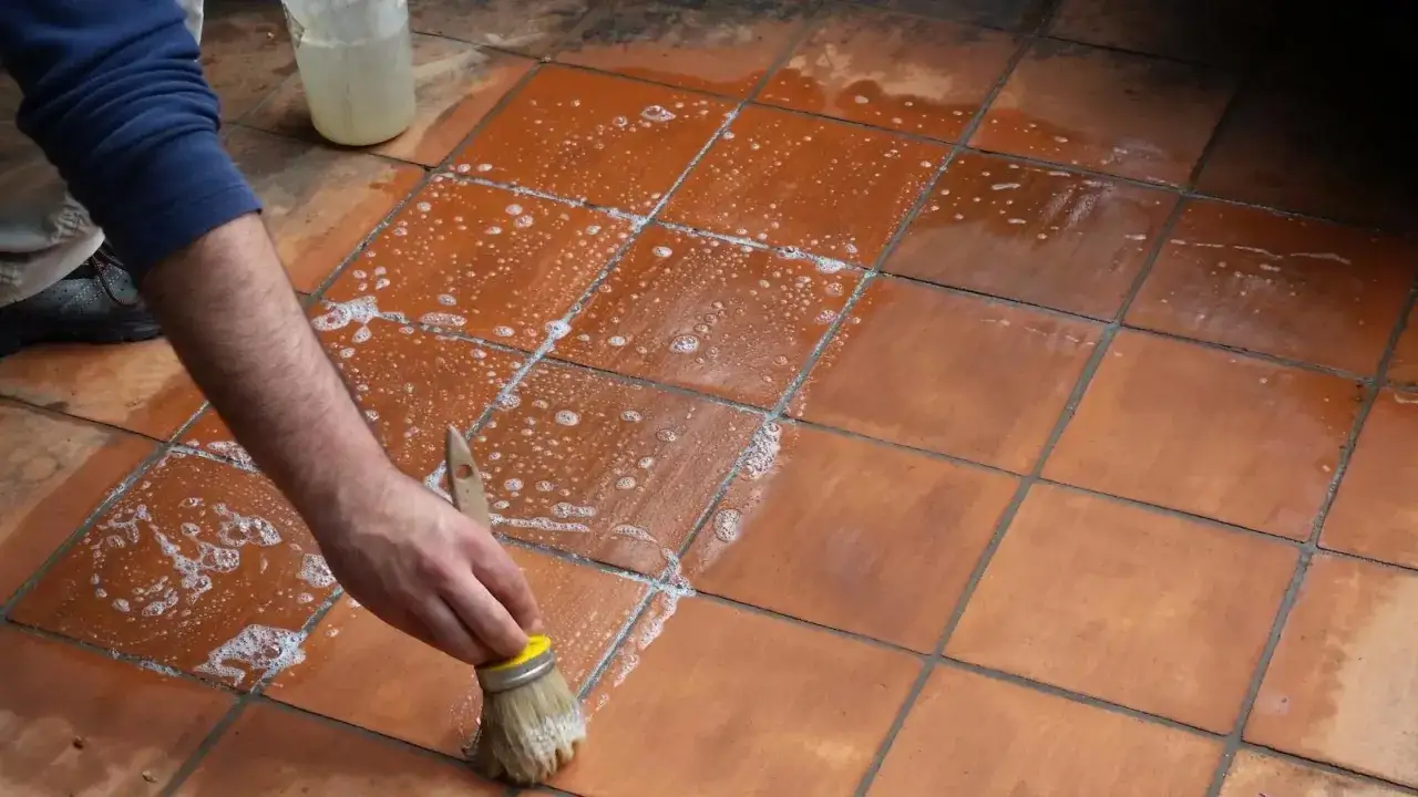 Mano che lava un pavimento poroso con una spazzola e schiuma.
