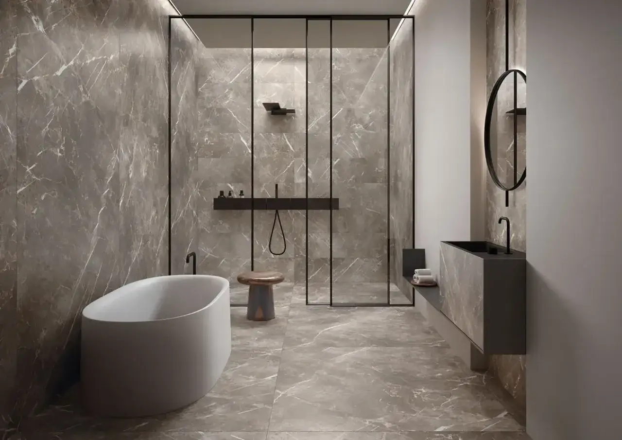 Bagni moderni con eleganti piastrelle effetto marmo grigio. Vasca freestanding, doccia a vista e lavabo sospeso creano un ambiente di lusso.
