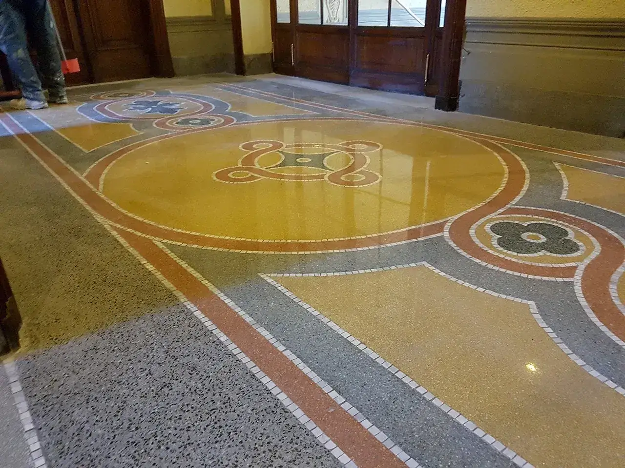 Pavimento in graniglia con motivi geometrici e floreali, tipico degli anni '50, con colori vivaci e finitura lucida.