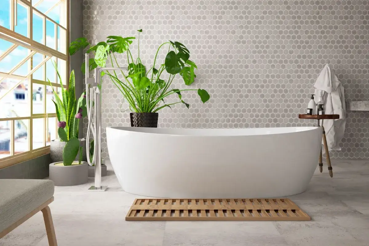 Vasca da bagno bianca freestanding, con piante verdi e rubinetteria moderna. Le dimensioni vasca da bagno sembrano generose, ideali per un bagno rilassante.