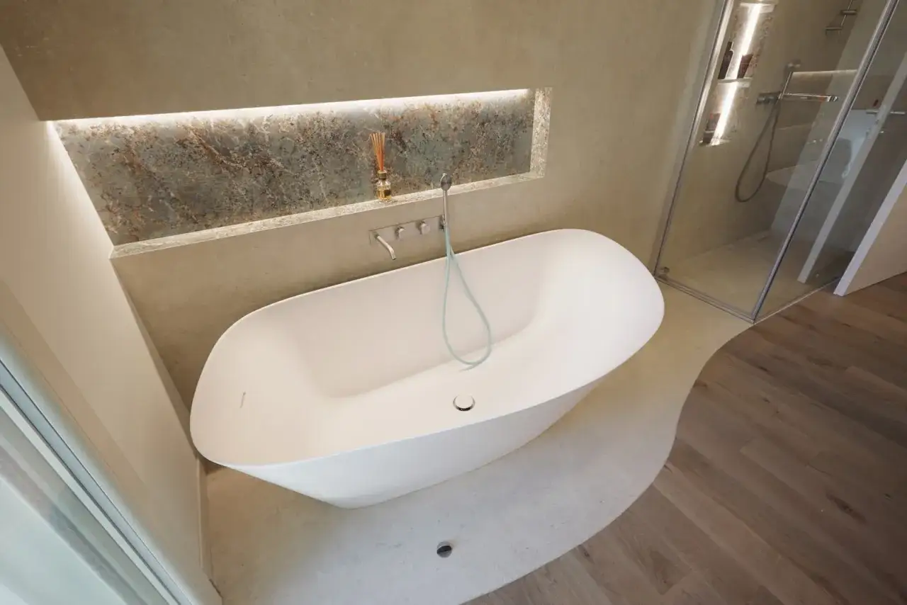 Bagno moderno con vasca freestanding e doccia a vista. La posa del rivestimento bagno crea un'atmosfera rilassante.