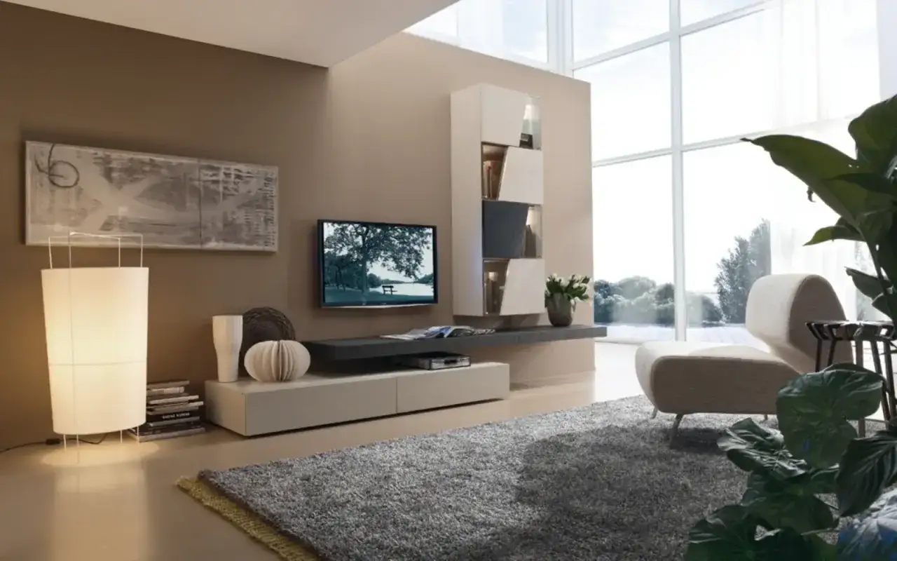 Soggiorno moderno con pareti color tortora, un mobile sospeso con TV, una poltrona di design e una grande finestra. Gli effetti pittura pareti moderne creano un'atmosfera accogliente.