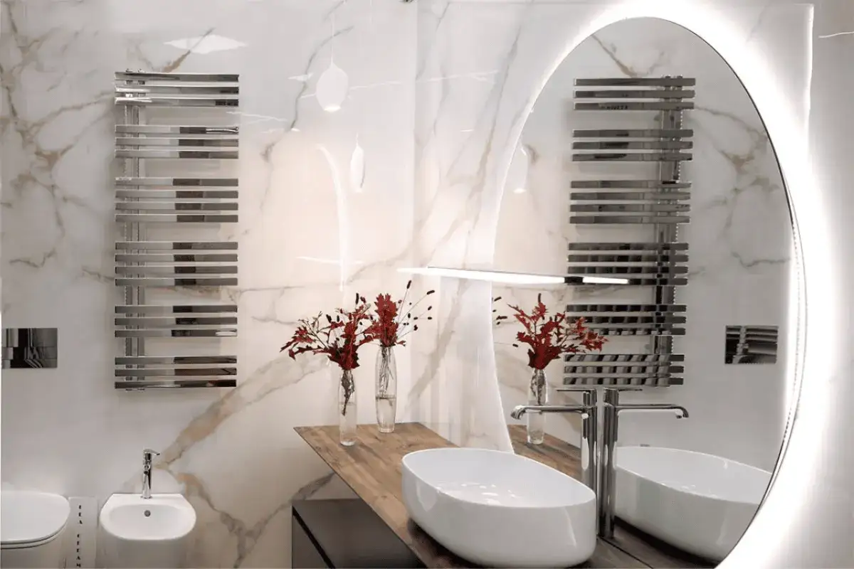 Bagno moderno con rivestimento in marmo, scaldasalviette cromato e lavabo ovale. Ottime idee rivestimento bagno per un look elegante.