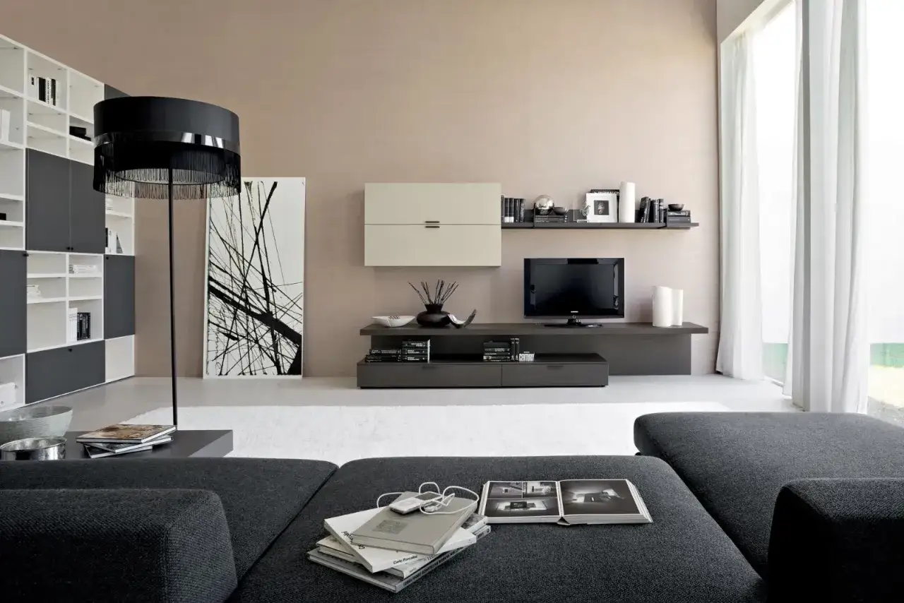 Soggiorno moderno con pareti color tortora e mobili scuri. Divano grigio, libreria componibile e un quadro astratto.
