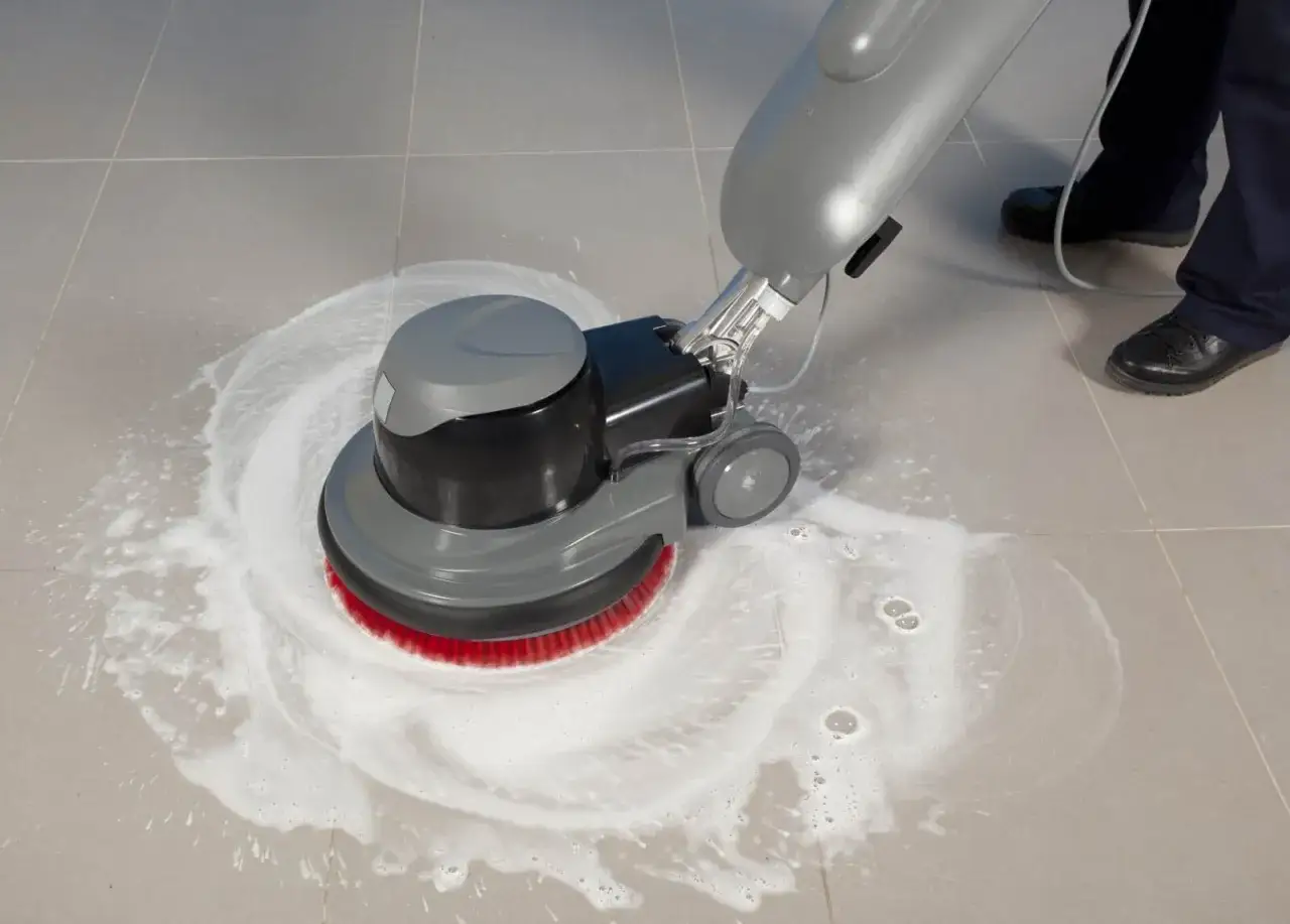Macchina lavapavimenti con spazzola rossa che pulisce un pavimento in gres con schiuma, ideale per capire come togliere la colla dal pavimento in gres.