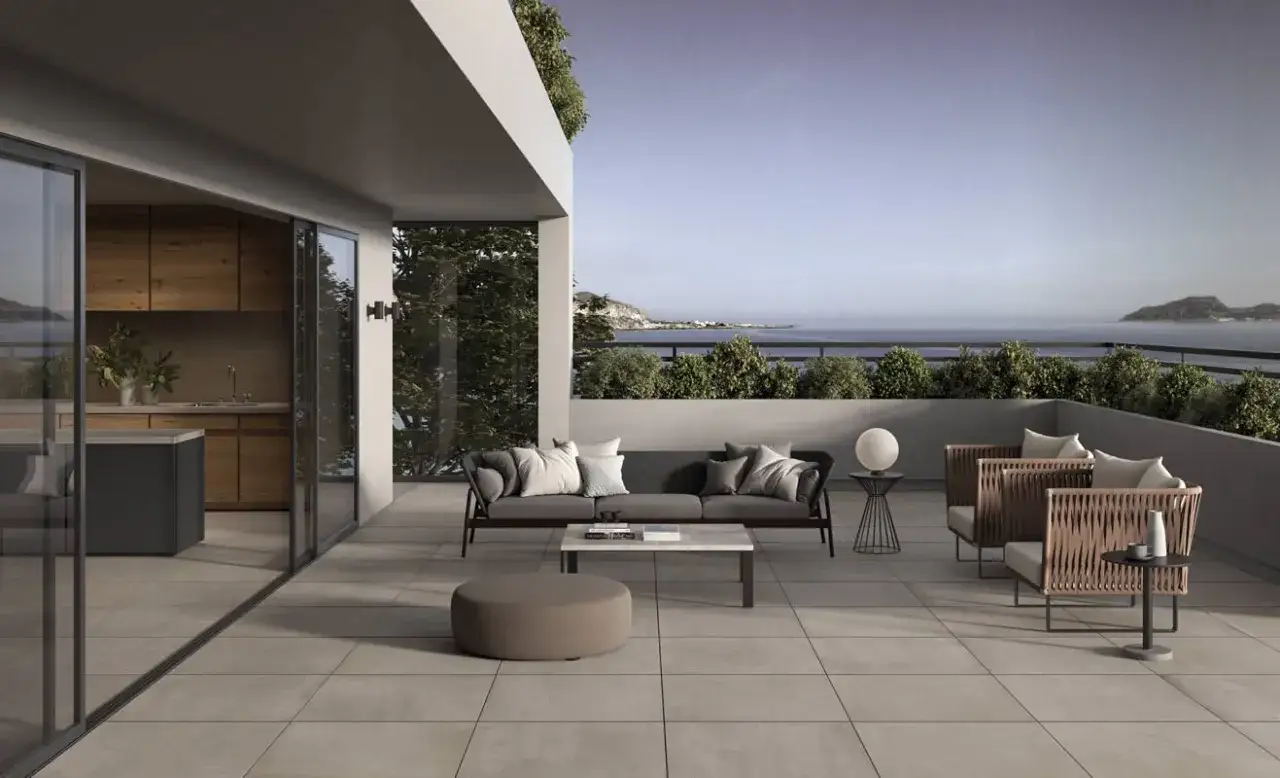 Terrazza moderna con divano, poltrone e tavolino, pavimentata in kerlite per esterni, con vista mare.