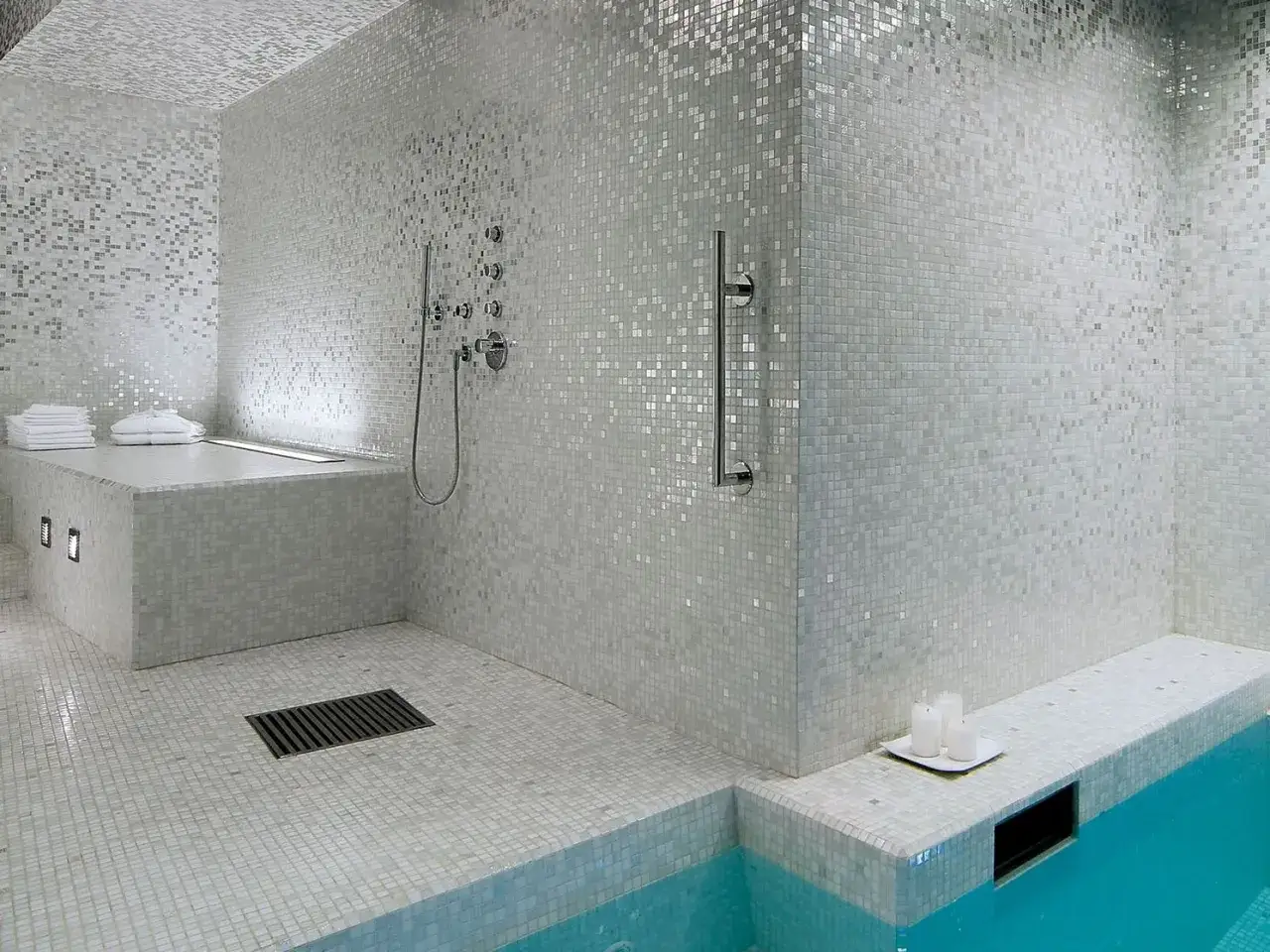 Bagno moderno con doccia e vasca, interamente rivestito con eleganti mosaici Bisazza bianchi e argentati che creano un effetto scintillante.